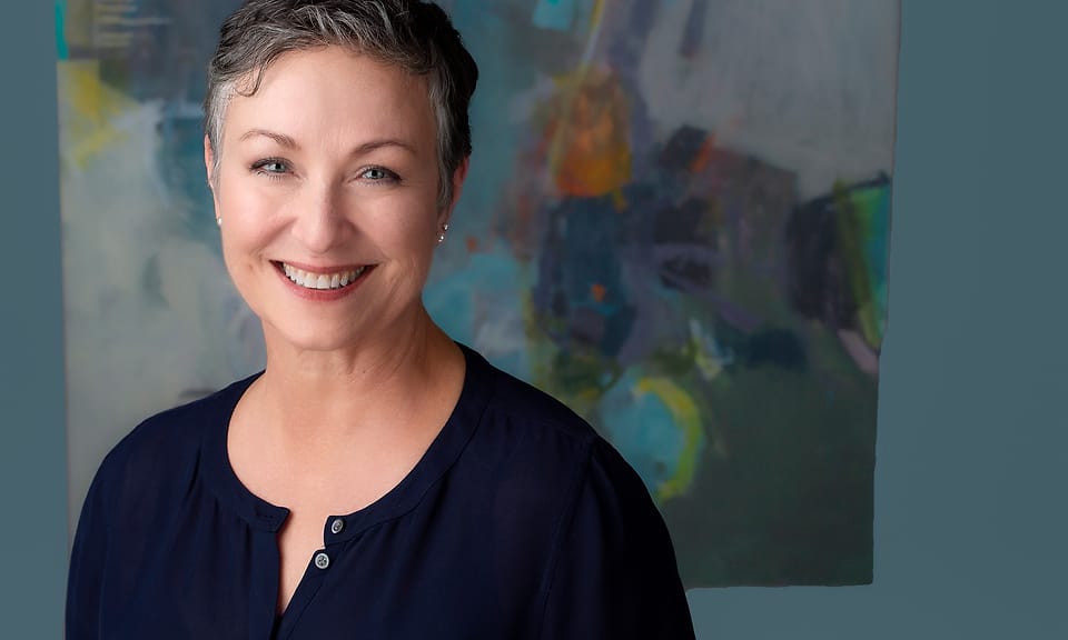 Personal branding portrait of Linda Gritta in front of an abstract painting