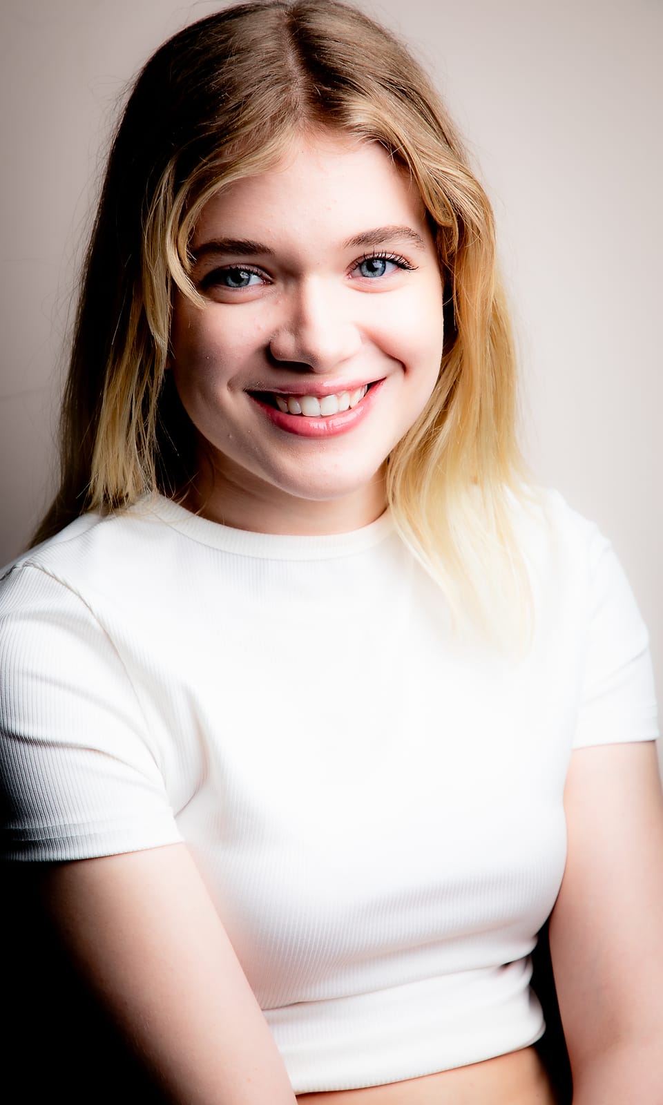 Bright editorial studio portrait of a young woman in a white crop top