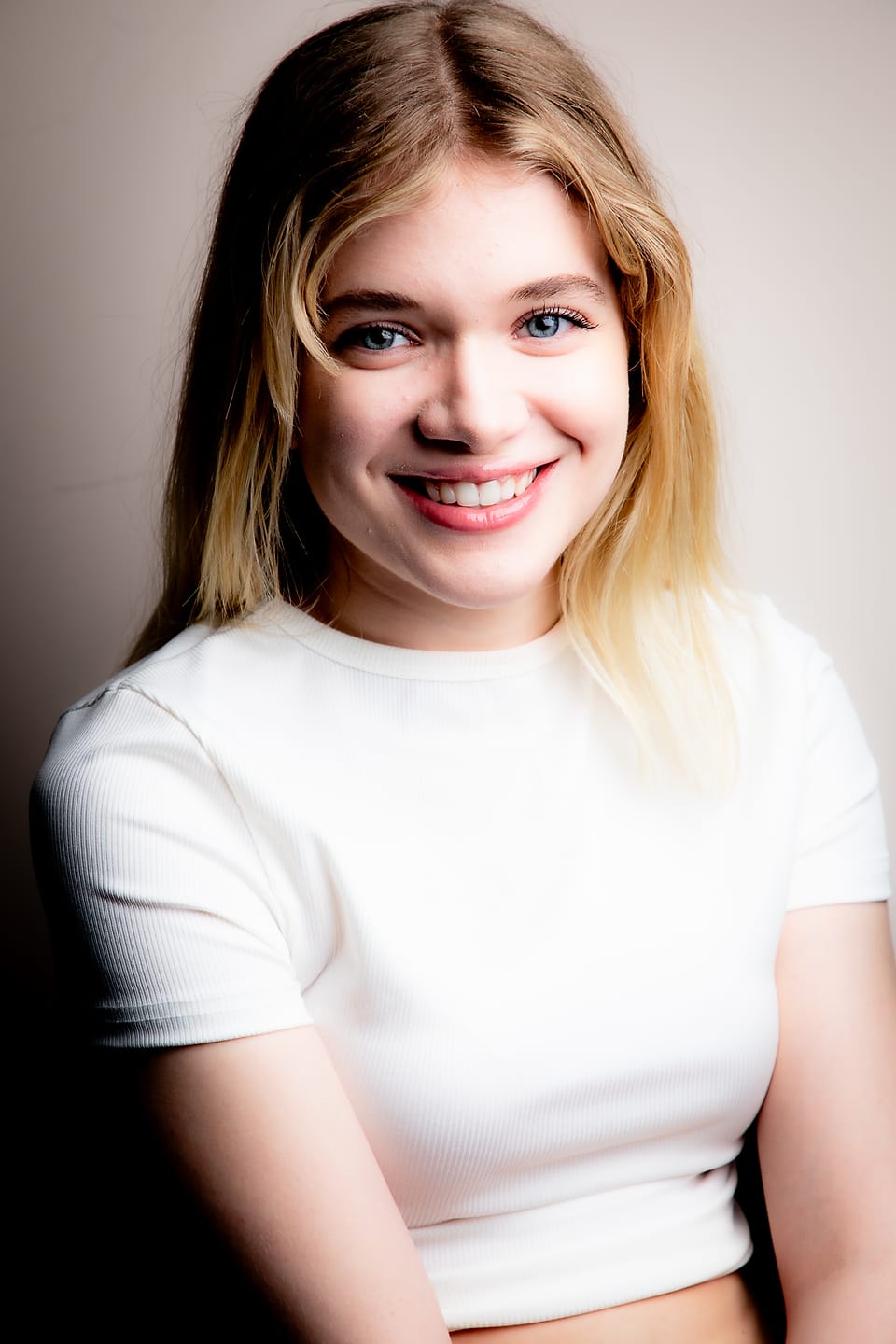 Bright editorial studio portrait of a young woman in a white crop top