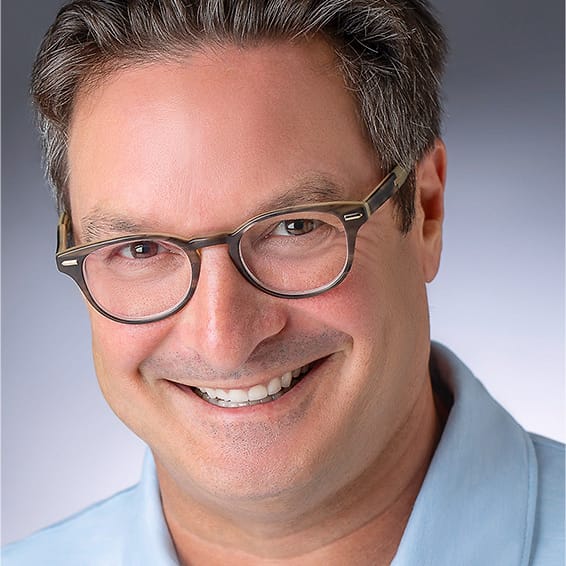 Approachable professional headshot of a man in glasses and a light blue polo