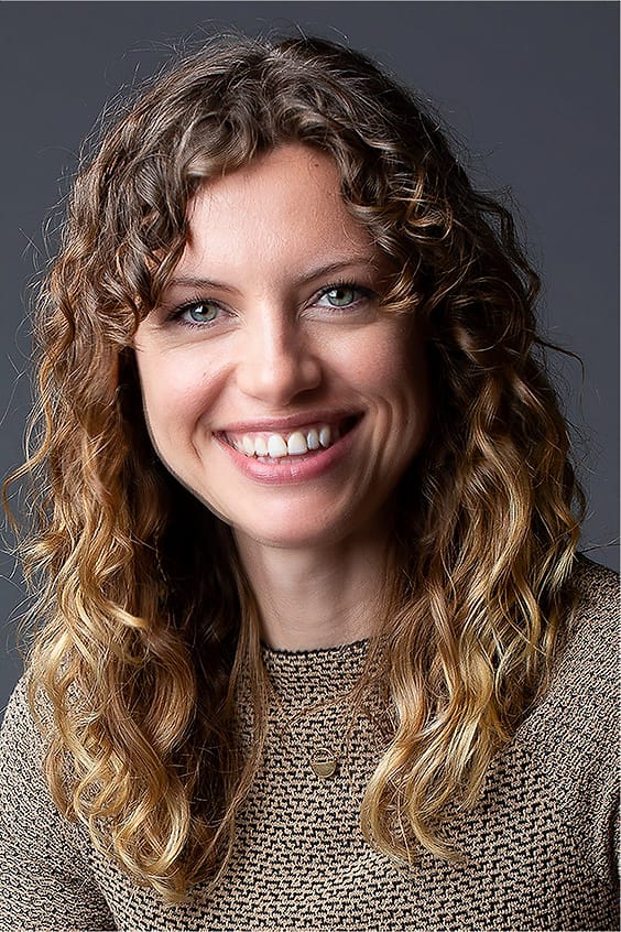 Warm studio portrait of a woman with curly hair in a textured knit top