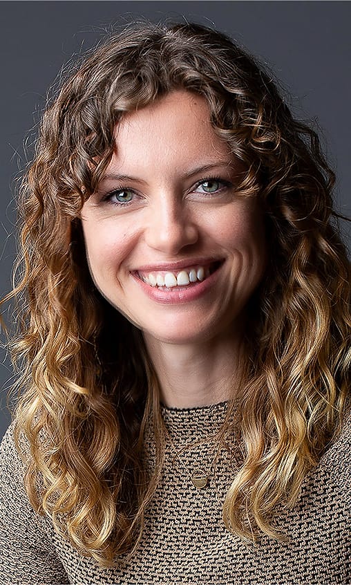 Warm studio portrait of a woman with curly hair in a textured knit top