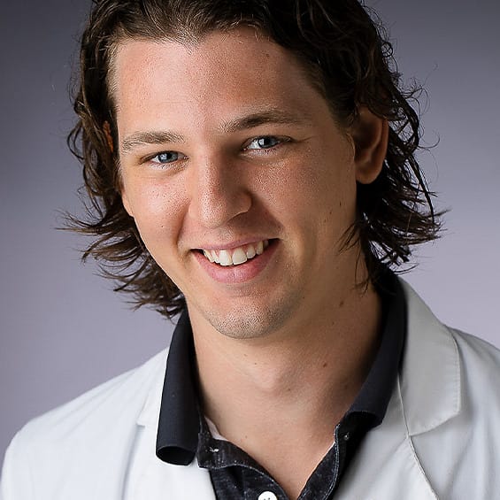 Healthcare team headshot of a young man in a white lab coat