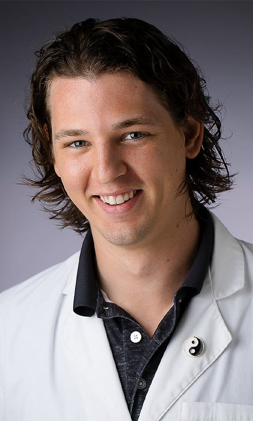 Healthcare team headshot of a young man in a white lab coat