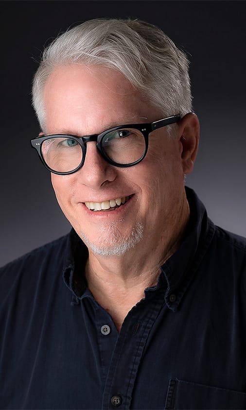 Professional portrait of a man with glasses in a navy button-down