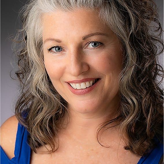 Creative portrait of a woman with gray-blonde hair in a blue off-shoulder top