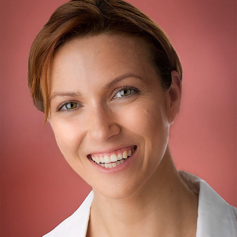 Healthcare corporate headshot of a woman in a white coat on a terracotta background