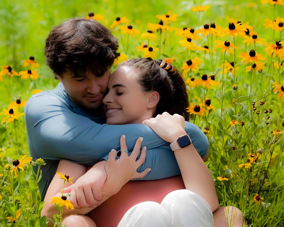 Couple in a close hug in a field of black-eyed Susans in Asheville