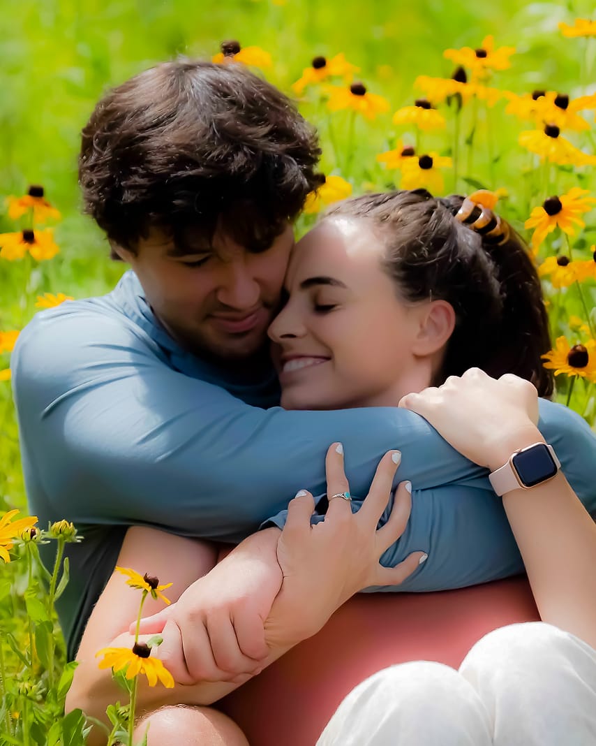 Couple in a close hug in a field of black-eyed Susans in Asheville